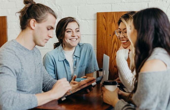 Drei junge Menschen sitzen an einem Tisch und unterhalten sich über die Arbeit
