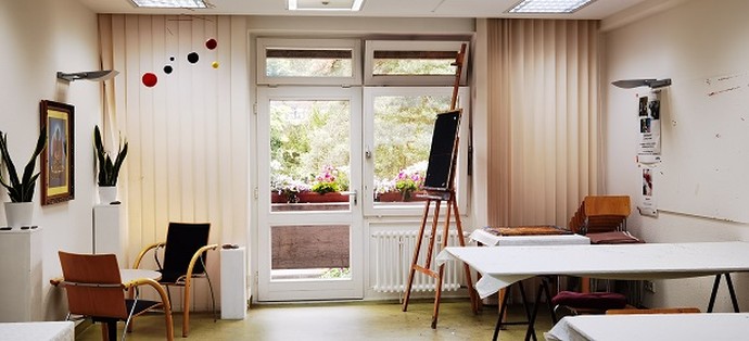 Freundlich gestalteter Raum mit Blick auf einen bepflanzten Balkon und eine Malerstaffelei im Raum