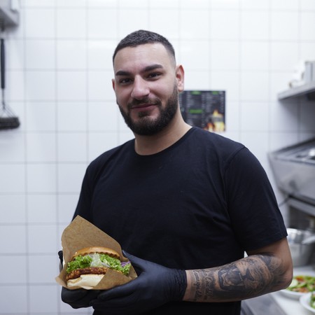 Mitarbeiter des Cafes mit selbstgemachtem Burger.