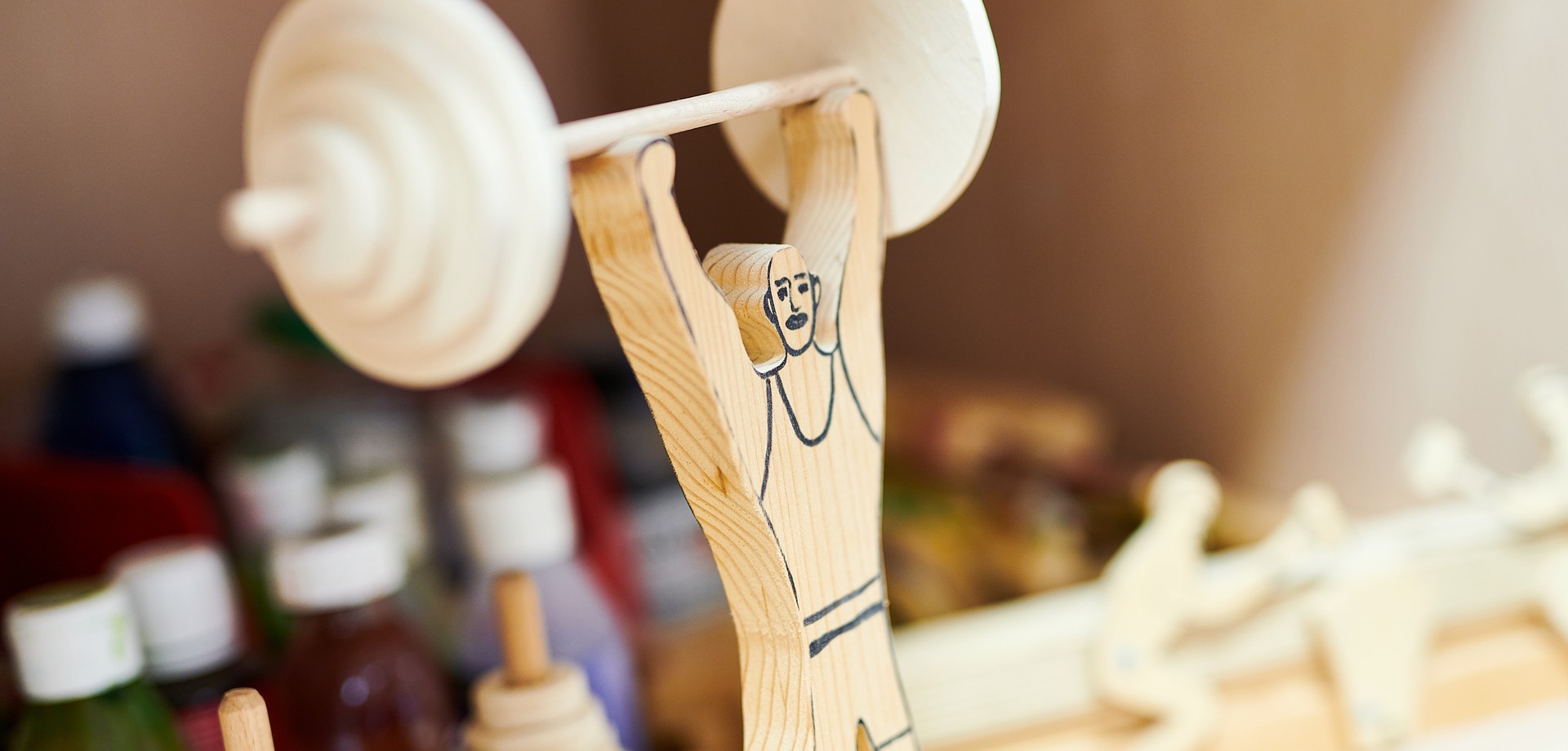 Eine geschnitzte Holzfigur stemmt eine Langhantel hoch