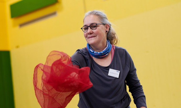 Sporttherapeutin Monika Kösters bei einer Übungmit bunten Tüchern.