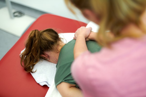Patientin erhält Massagetherapie im Nacken.