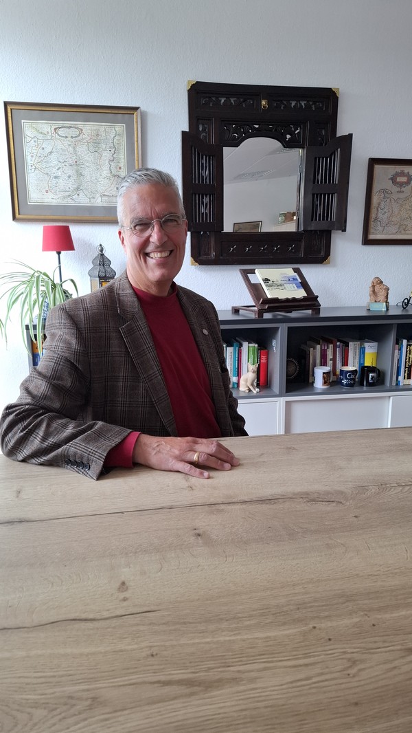 Dr. med. Holger Lach sitzt lächelnd an seinem Schreibtisch